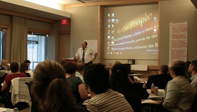 Scholars in a lecture hall with presenter at the main screen